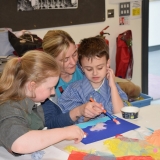 Picture of a staff member assisting two pupils with their  art work