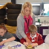 Picture of a pupil cutting out a shape in clay assisted by a staff member