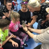 Picture of staff and several  pupils looking at a small mammal