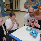 Picture of a teacher with students examining the Dash robot