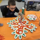 Picture of a pupil painting and decorating the large  wooden outline of a  human cell