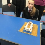 Photograph of pupil testing the strength of bridge made of uncooked spaghetti