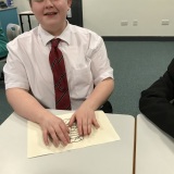 Photograph of a pupil using their fingers to feel a shape on raised paper