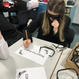 photograph of pupil wearing glasses that simulated being visually impaired while trying to complete a task