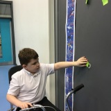 Photograph of a pupil adding their height to a height chart