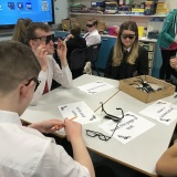 photograph of several pupils wearing glasses that simulated being visually impaired while trying to complete a task