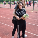 Photograph of a pupil with a rugby ball being guided by a staff member