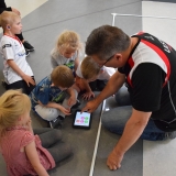 Photograph of a  development officer teaching pupils how to use the iPad to control the sphere shaped robot