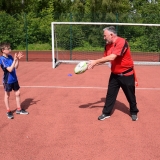 Photograph of a ruby development officer demonstrating to a pupil how to pass a rugby ball